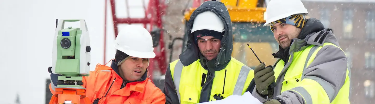 trabajadores con chalecos de seguridad y cascos en un sitio de construcción en invierno