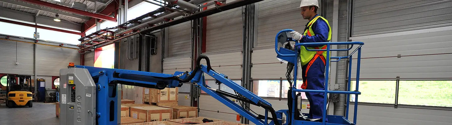 Trabajador en una brazo de elevación eléctrico dentro de un almacén