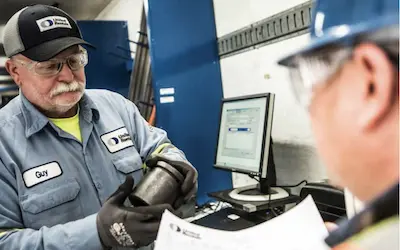 dos trabajadores que conversan sobre el repuesto de un equipo en un mostrador