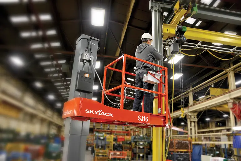 Trabajador en un elevador eléctrico para una persona Skyjack naranja