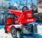 Rear view of a red Magni telehandler with boom retracted and black tires positioned outdoors on snowy terrain.