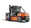 Rear angled view of an orange and black Toyota warehouse forklift with a black mast and orange forks with an enclosed cabin.