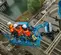 Top angled view of three workers on an elevated blue boom lift platform on a construction site.