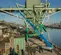 Wide side view of extended blue boom lift on a construction site near a river.
