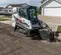 Cargador sobre orugas compacto BOBCAT blanco y negro que excava tierra con suciedad