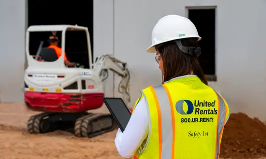 mujer en un lugar de trabajo sosteniendo un ipad junto a un cargador compacto