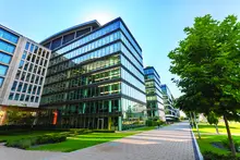 stock image of the outside of a glass office building near trees under a blue sky