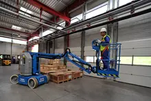 Trabajador en una brazo de elevación eléctrico dentro de un almacén